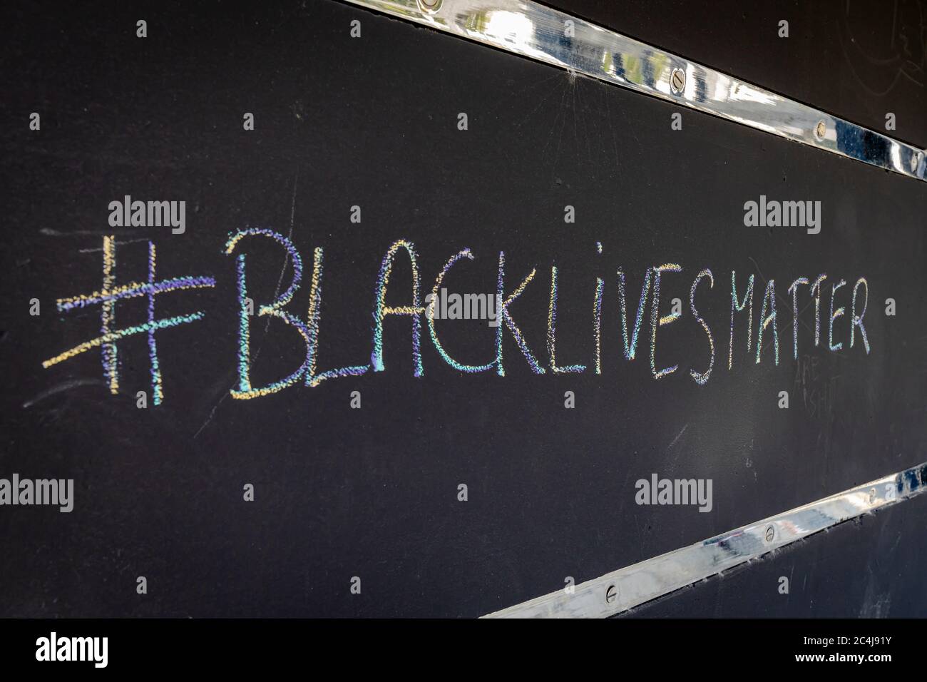 La frase BlackLivesMatter preludato da un hashtag calato su uno sfondo nero, con una striscia di metallo brillante sopra e sotto il testo. Foto Stock