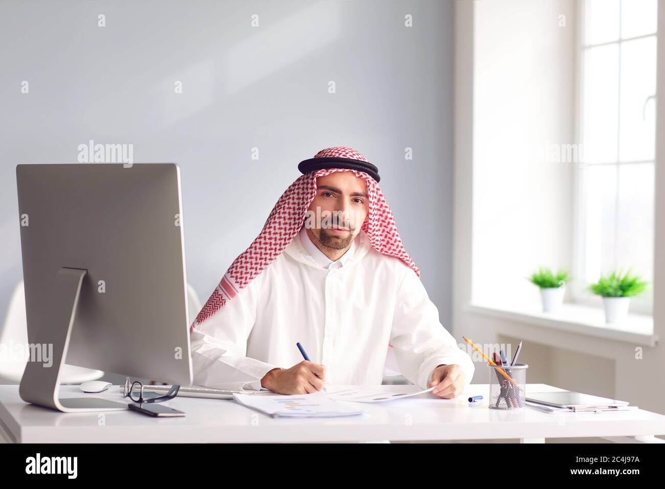 Il calmo uomo arabo siede ad un tavolo nell'ufficio. A. Foto Stock