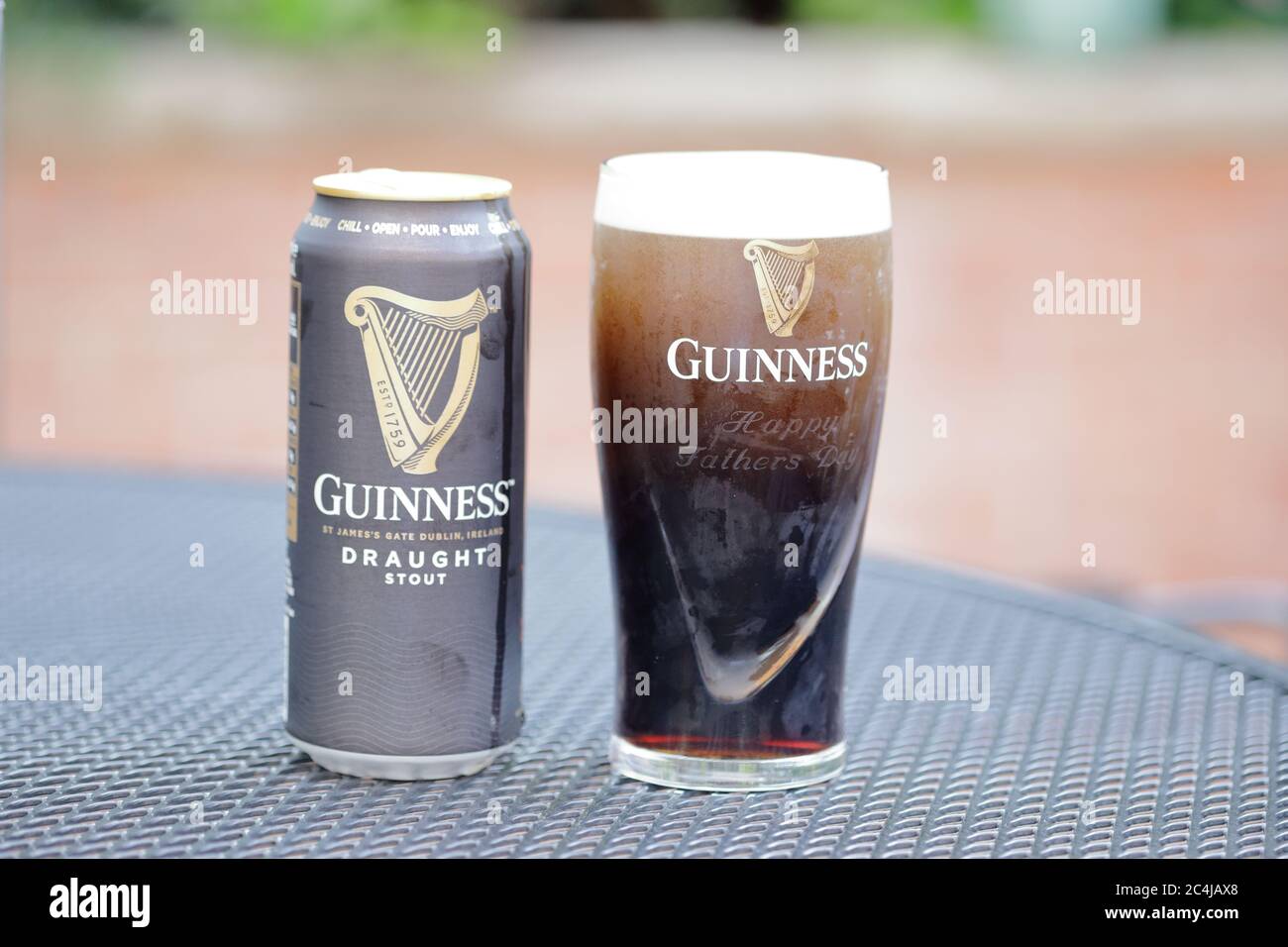 Un bicchiere di Guinness ancora stabilirsi e può, all'esterno su un tavolo da patio Foto Stock