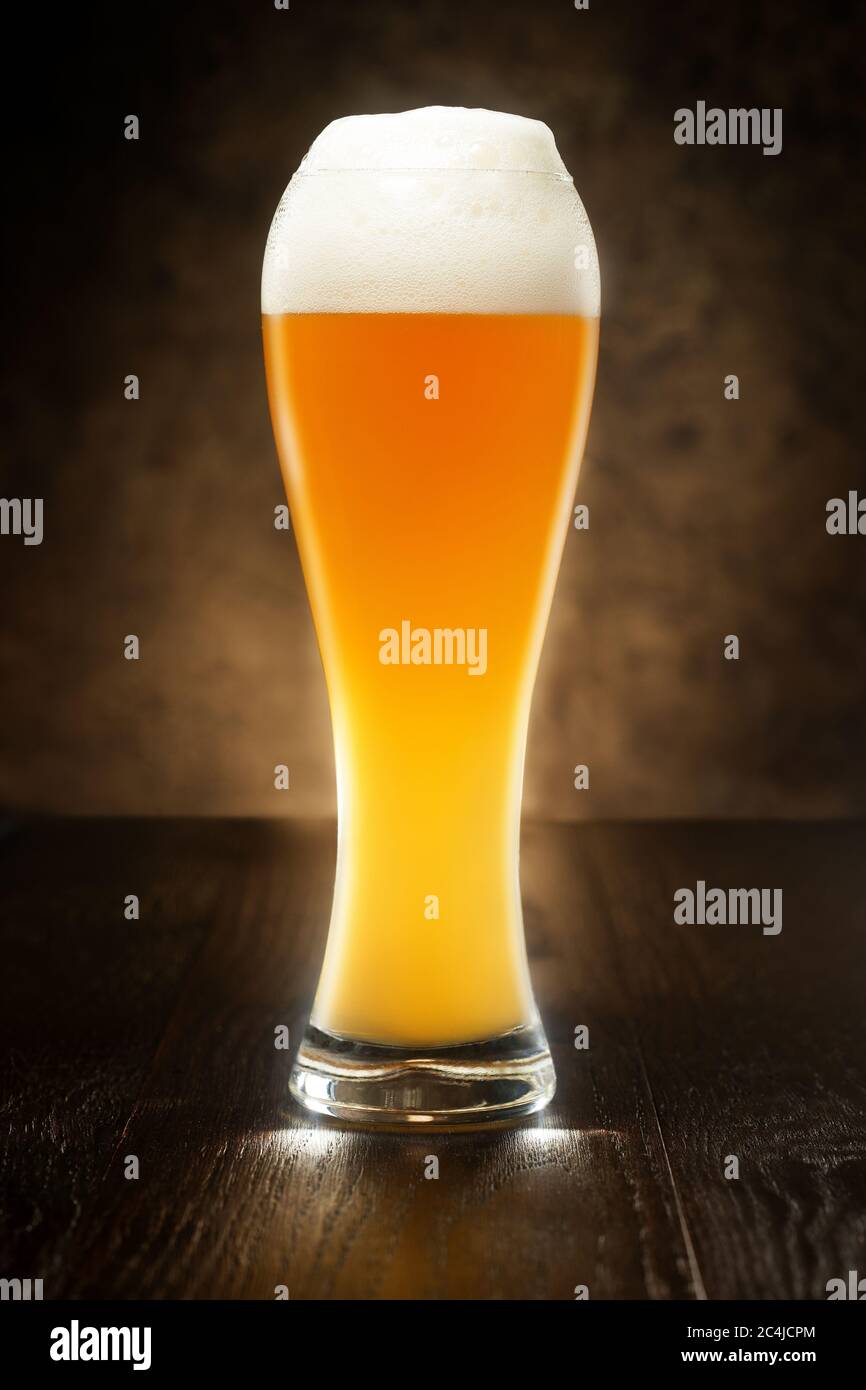 bicchiere di birra su un tavolo di legno isolato su sfondo scuro Foto Stock