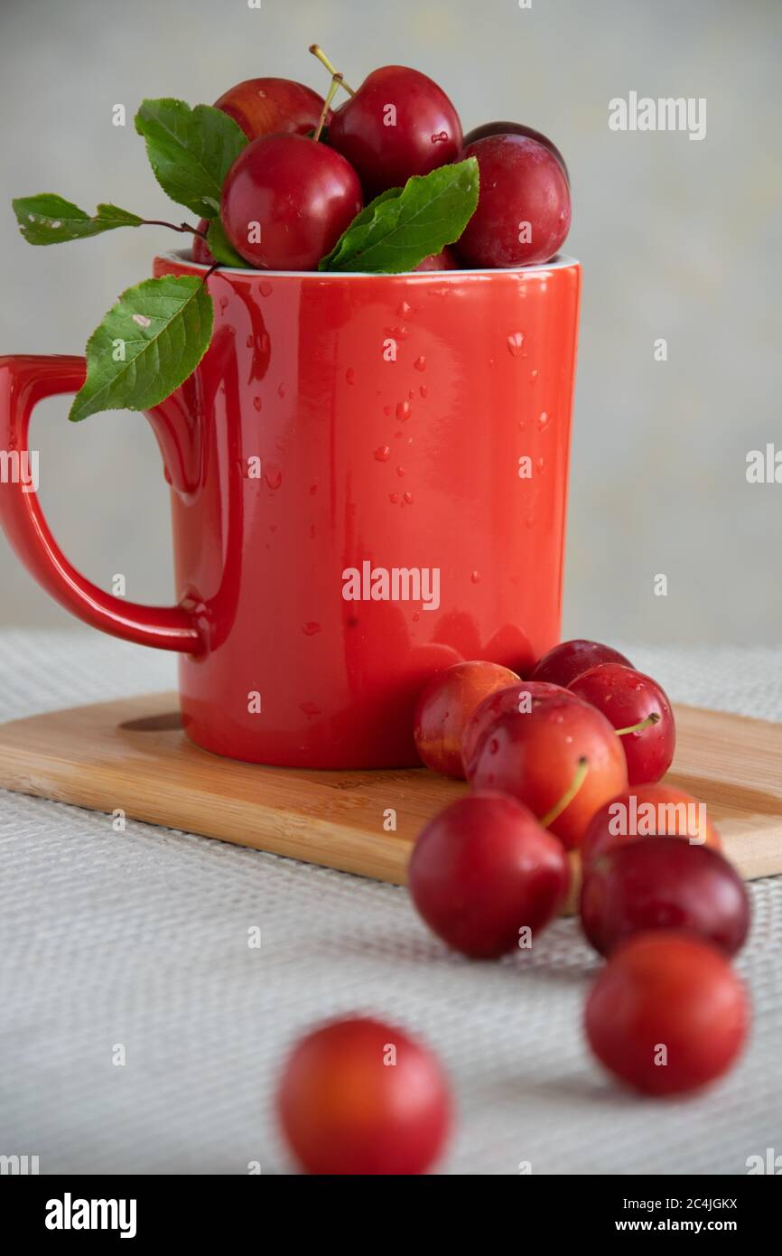 Prugne fresche in tazza rossa, cibi dolci sani Foto Stock