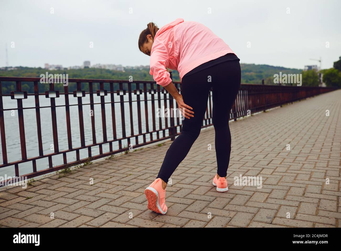 Sportiva che soffre di dolore alle gambe durante il suo allenamento all'aperto, spazio vuoto. Corridore con lesioni sportive all'esterno Foto Stock
