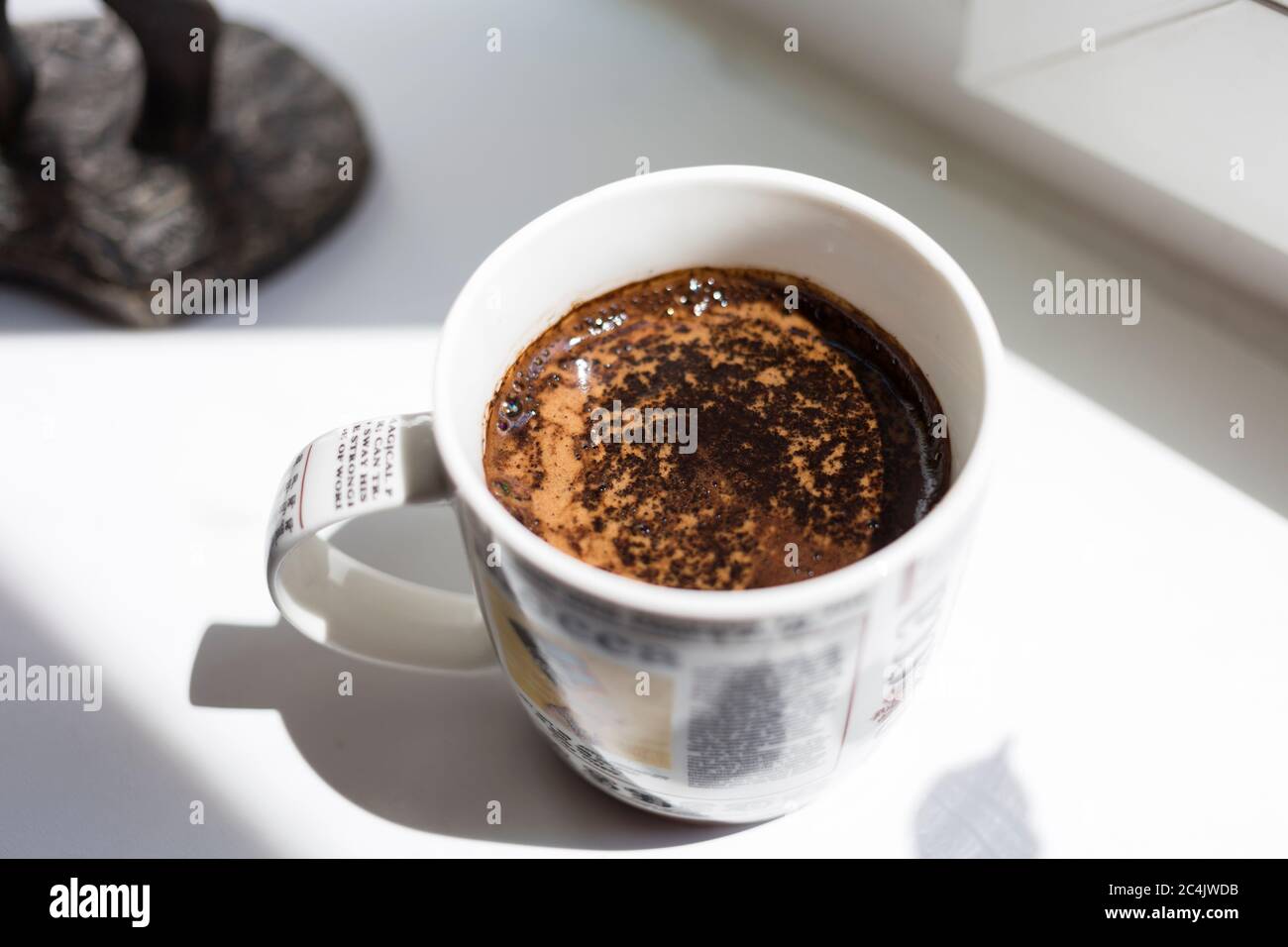 Vista con la parte superiore della tazza di caffè. Primo piano. La tazza di caffè si trova su uno sfondo bianco. Foto Stock