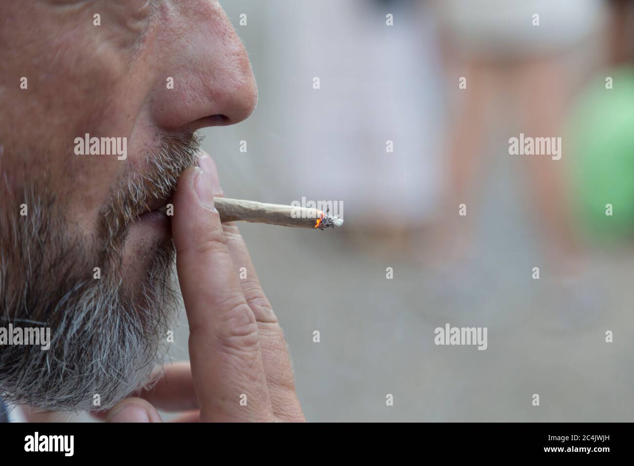 Sopportato un uomo che fumava una sigaretta. Primo piano. È presente un ritratto del profilo esterno con messa a fuoco selettiva. Foto Stock