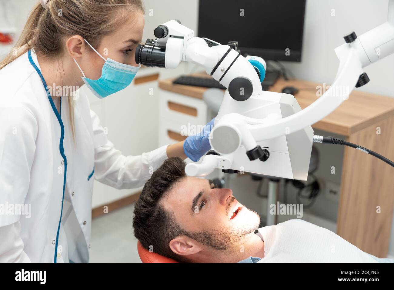 Dentista che controlla i denti del paziente presso l'ufficio di clinica odontoiatrica. Microscopio, trattamento dentistico professionale Foto Stock