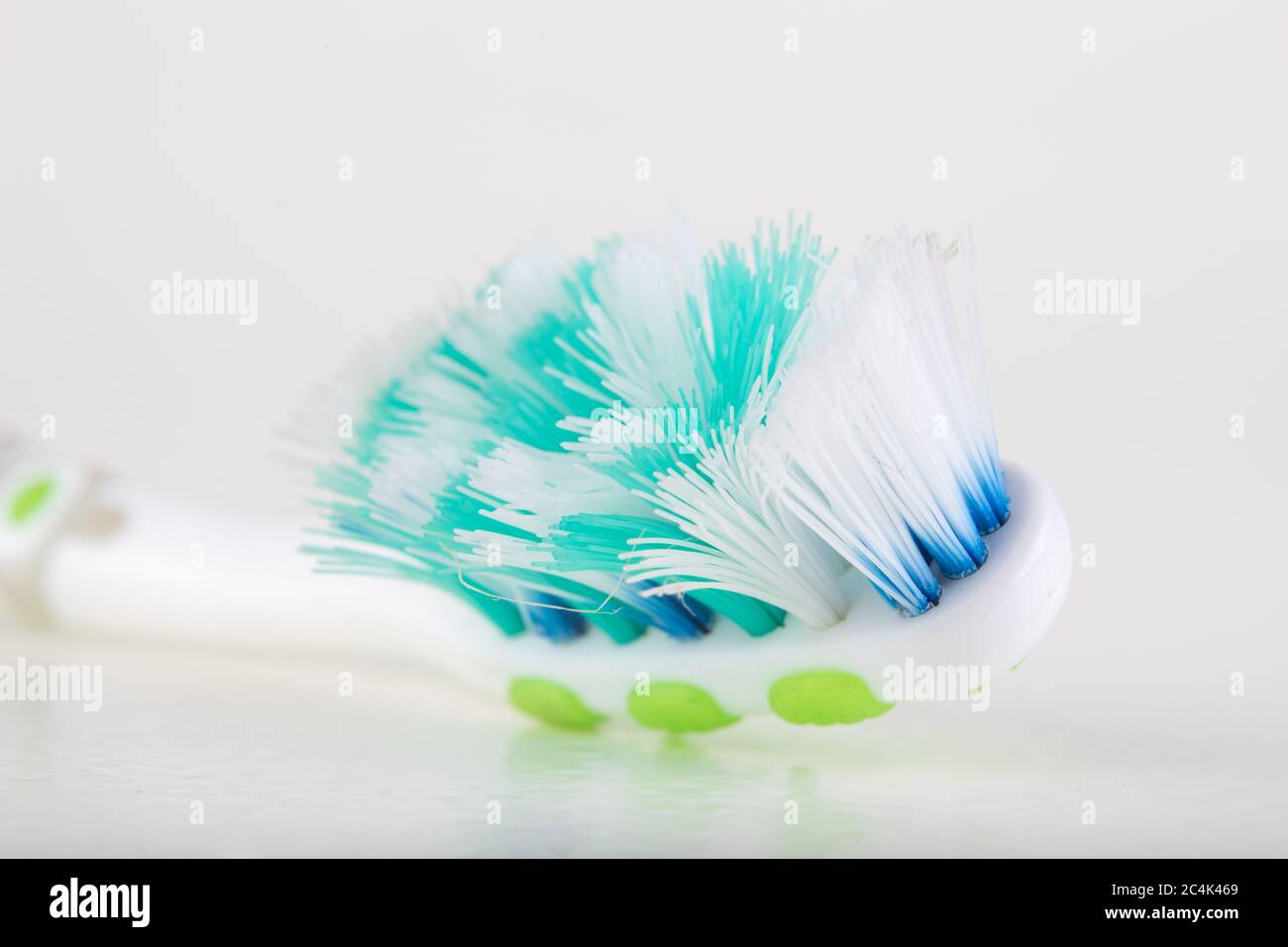 Spazzolino da denti su un tavolo bianco. Setole molto usurate in una spazzola per l'igiene personale. Sfondo chiaro. Foto Stock