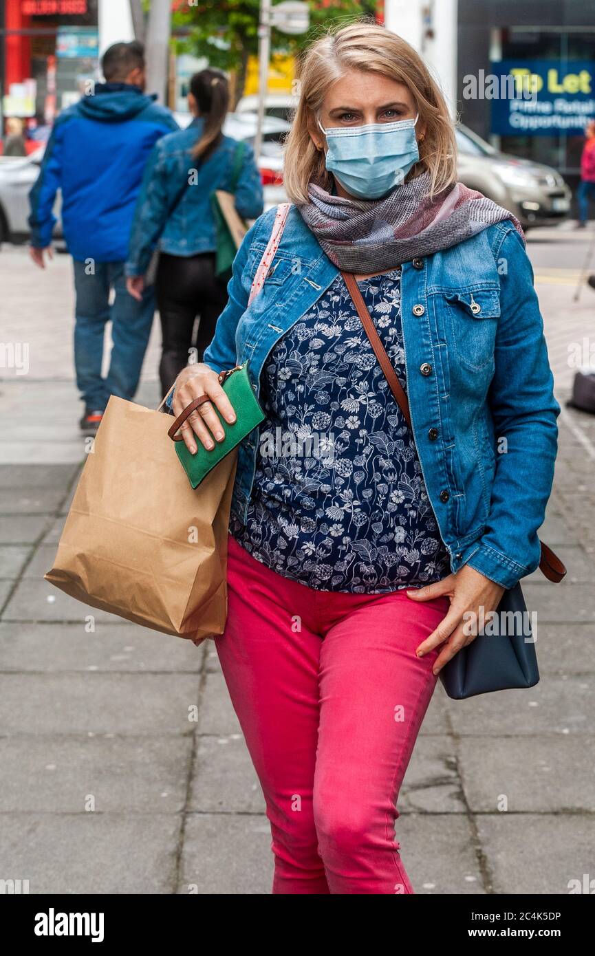 La donna bionda indossa una maschera a Cork City, Irlanda, per proteggersi da Coronavirus/Covid-19 mentre si acquista. Foto Stock