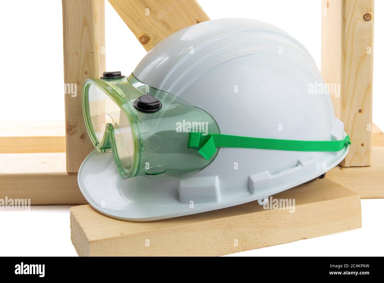 un elmetto bianco con occhiali di sicurezza verdi poggiati su strutture in legno Foto Stock