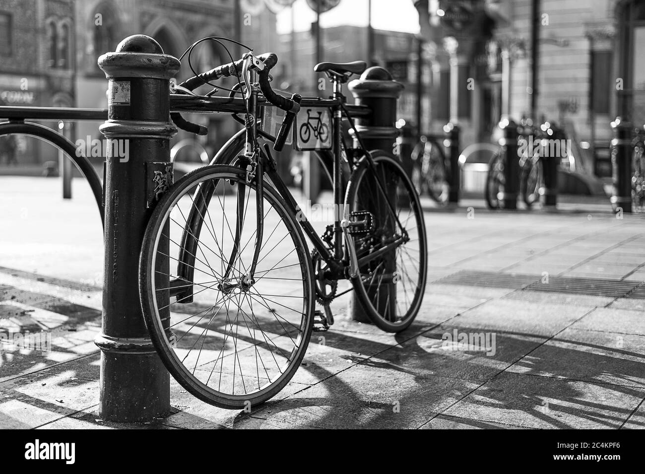 Tiro in scala di grigi di una bicicletta parcheggiata da un posto in la città Foto Stock