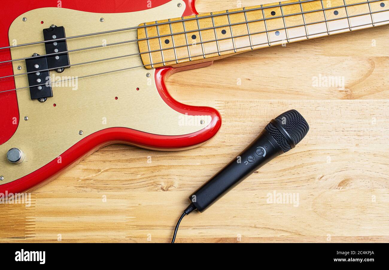 Chitarra basso elettrica rossa Fiesta e microfono USB su legno tabella Foto Stock