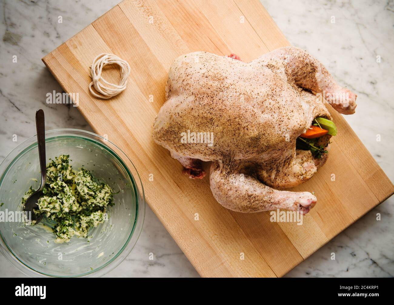 Preparazione per il trussing di un pollo farcito con erbe e verdure Foto Stock