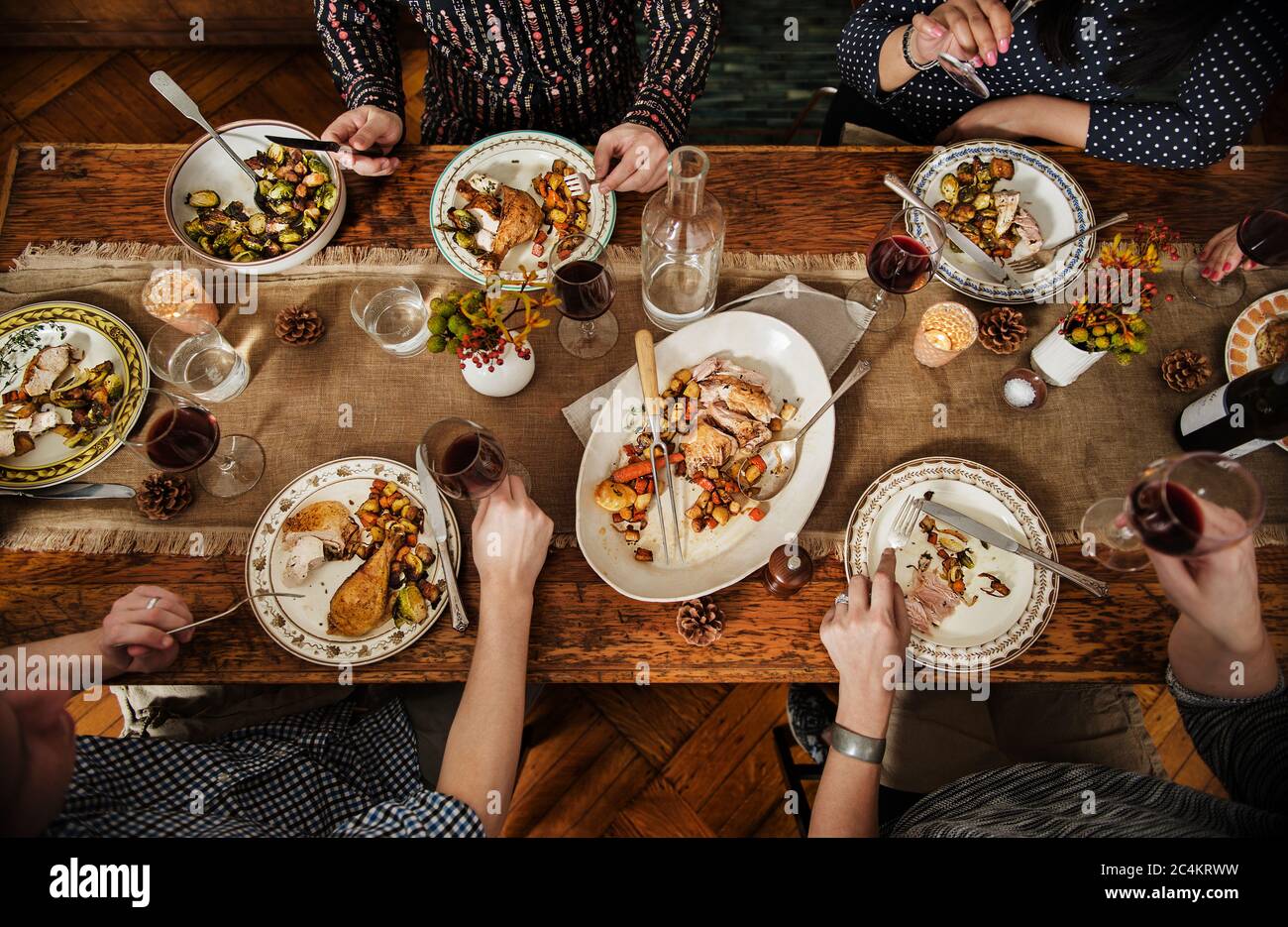 La gente si diverre con una cena autunnale con pollo arrosto, patate dolci germogli di brussel e vino rosso Foto Stock