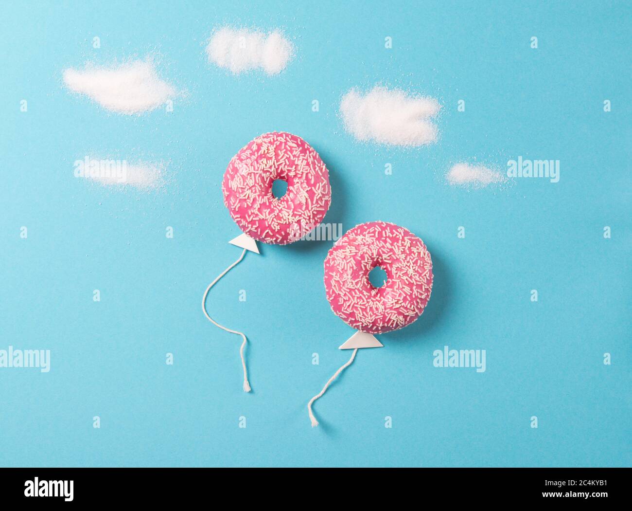 Ciambelle rosa su sfondo blu, minimalismo creativo alimentare, ciambelle a forma di palloncino nel cielo con nuvole di zucchero, vista dall'alto Foto Stock