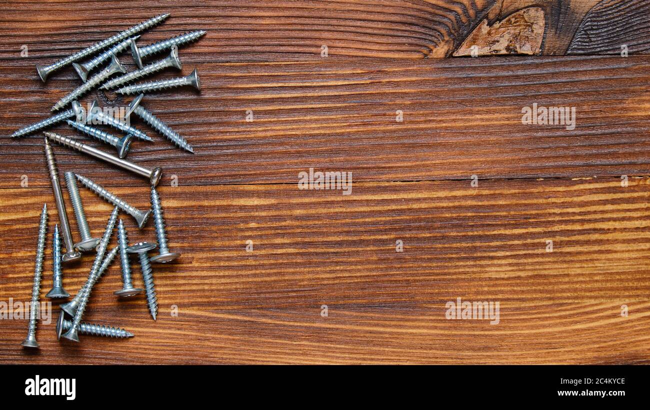 Viti metalliche di tipo diverso su sfondo in legno con spazio per la copia e vista dall'alto. Foto Stock