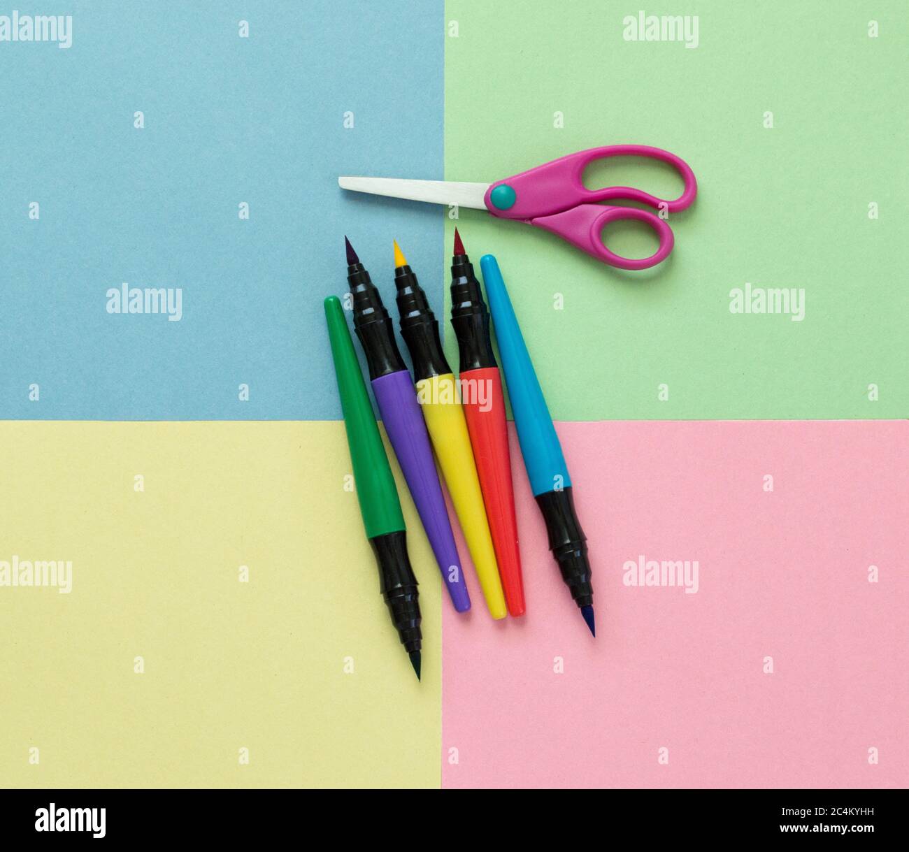 5 pennarelli colorati e un paio di forbici per bambini su quadrati multicolore di carta da costruzione Foto Stock