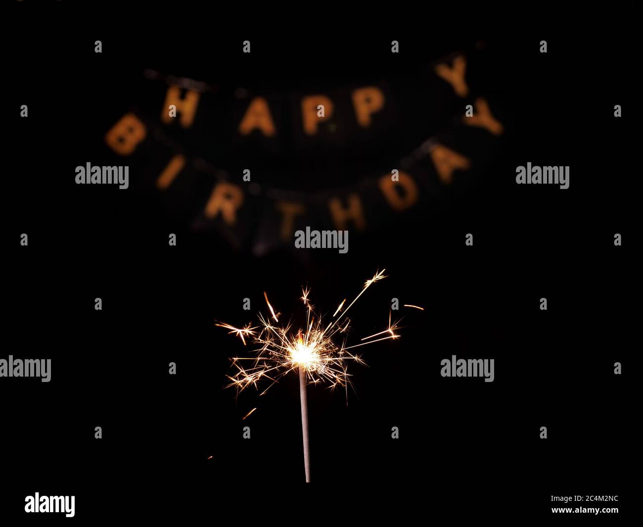 Primo piano di Sparkler su sfondo nero isolato con iscrizione Happy Birthday in lettere d'oro. Le riprese vengono riprese in 4k da un treppiede sotto l'illuminazione artificiale professionale Foto Stock