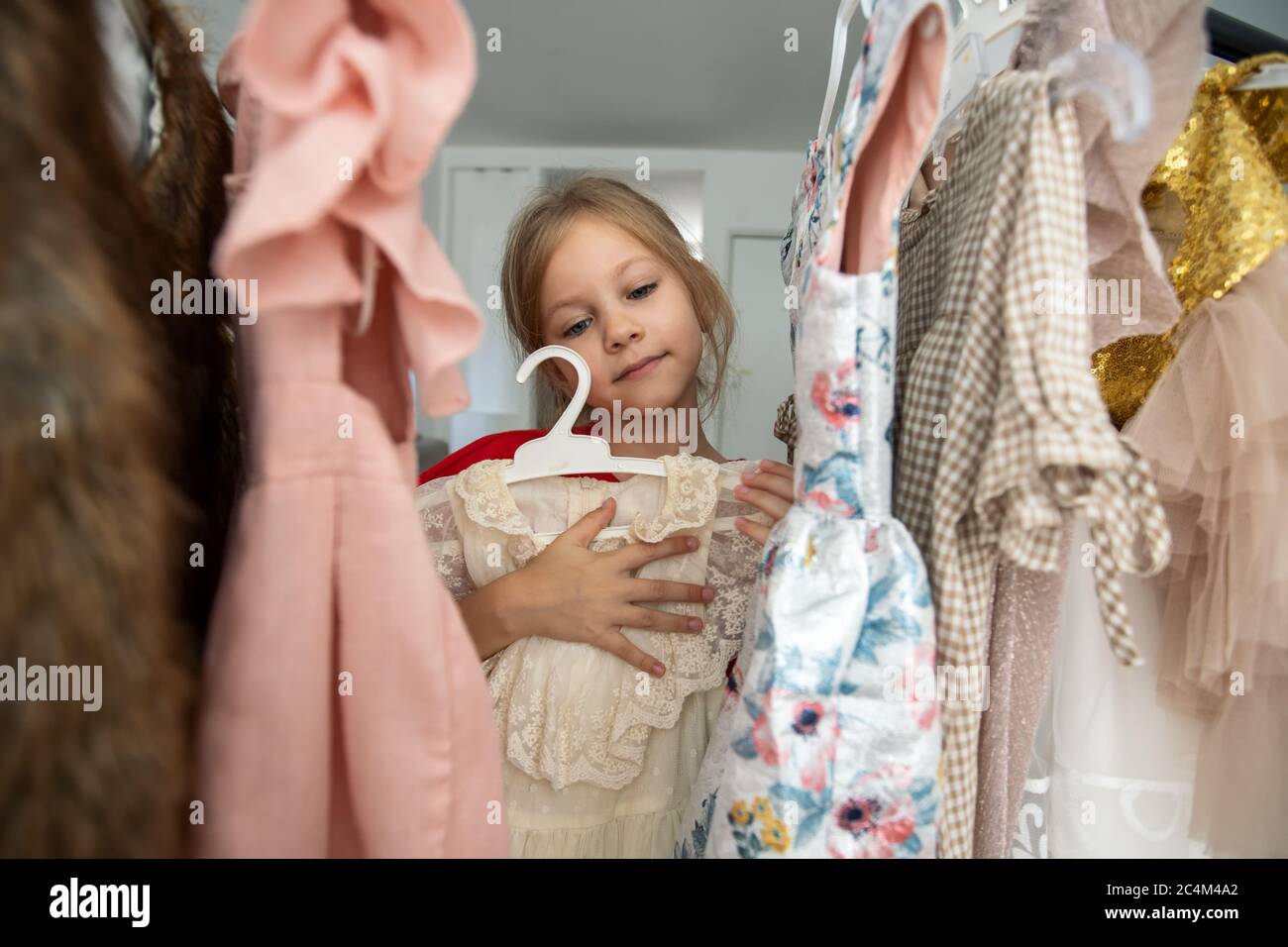 Ragazza piccola cute che sceglie i vestiti in stanza di vestiario Foto Stock