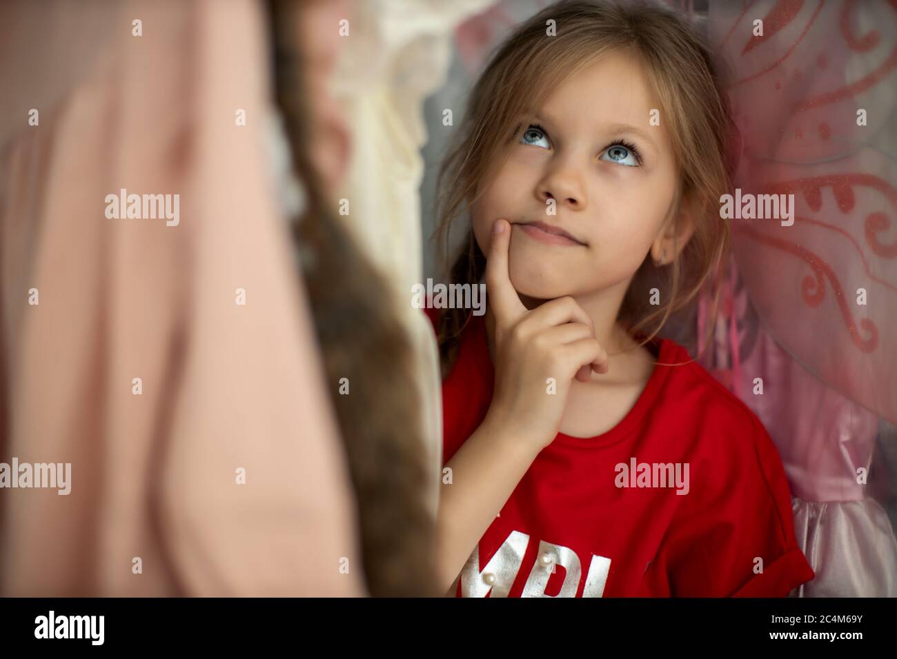 Soft Focus di un bambino di 5-6 anni scegliendo i suoi abiti da Kids Cloth rack in negozio di abbigliamento. Shopaholics ragazza Foto Stock
