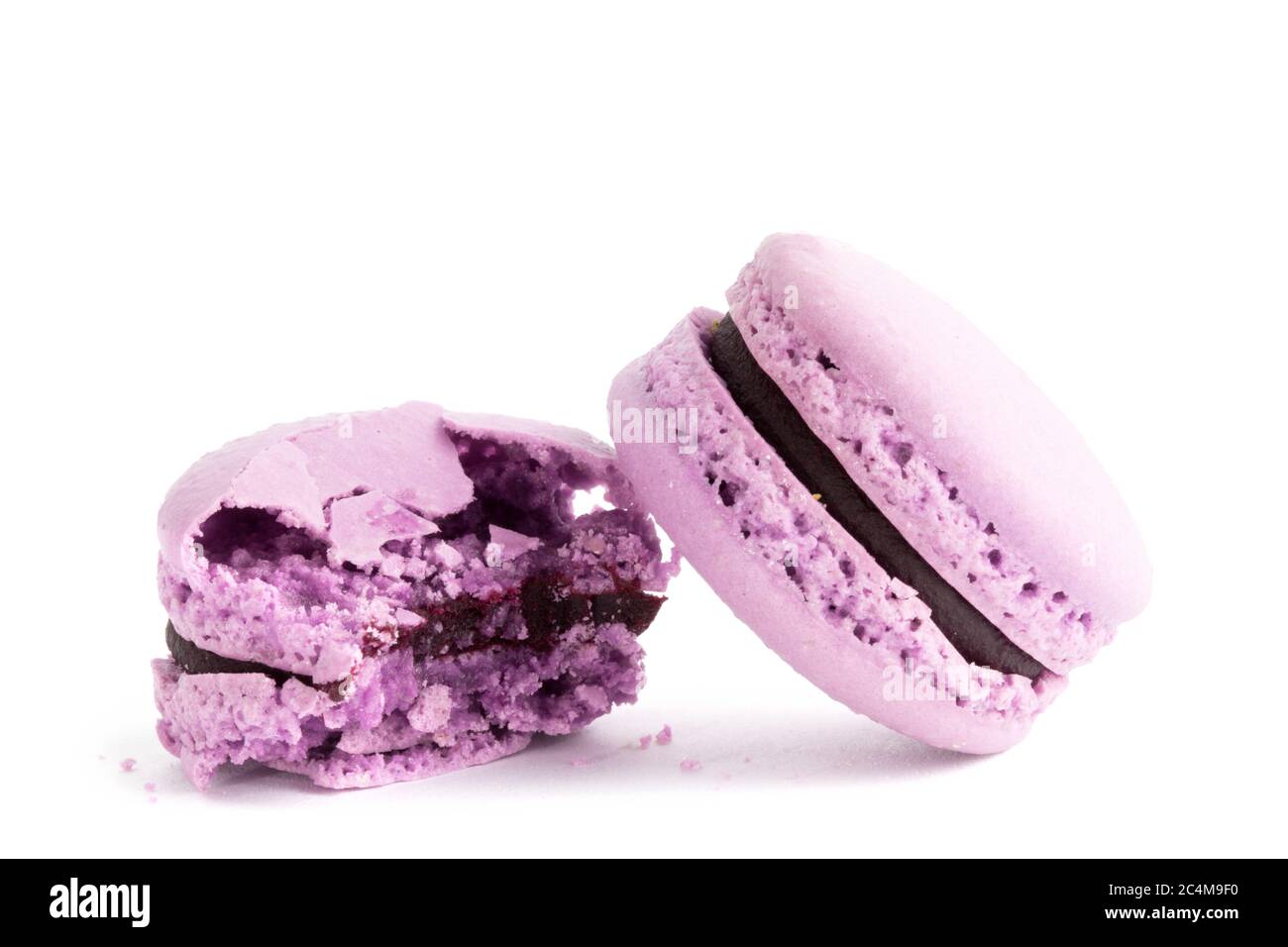 macro closeup di biscotti viola macaroon con un morso di uno su uno sfondo bianco Foto Stock