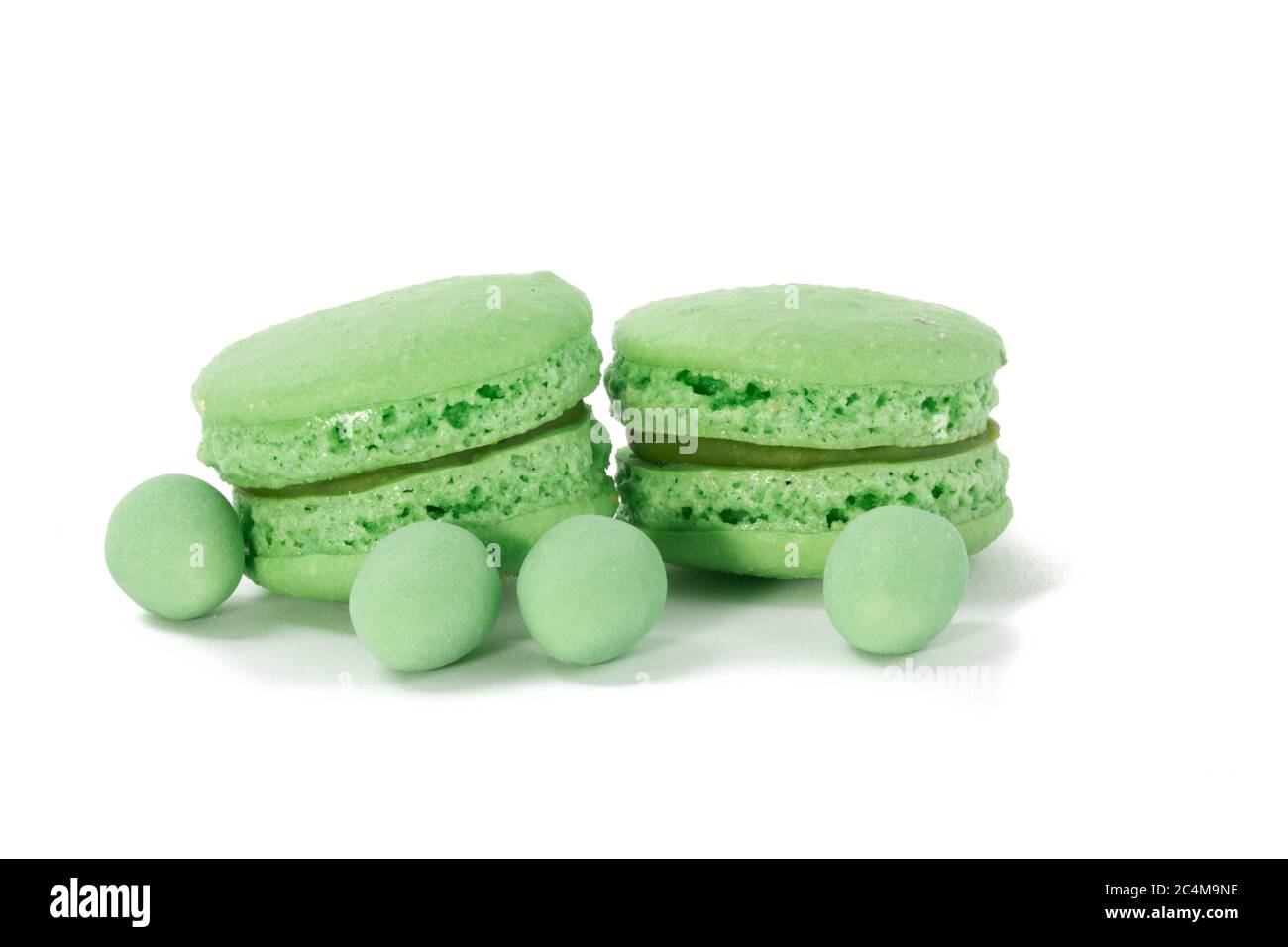 Primo piano di biscotti verdi di meringa macaroon e mini uova verdi di Pasqua su sfondo bianco Foto Stock