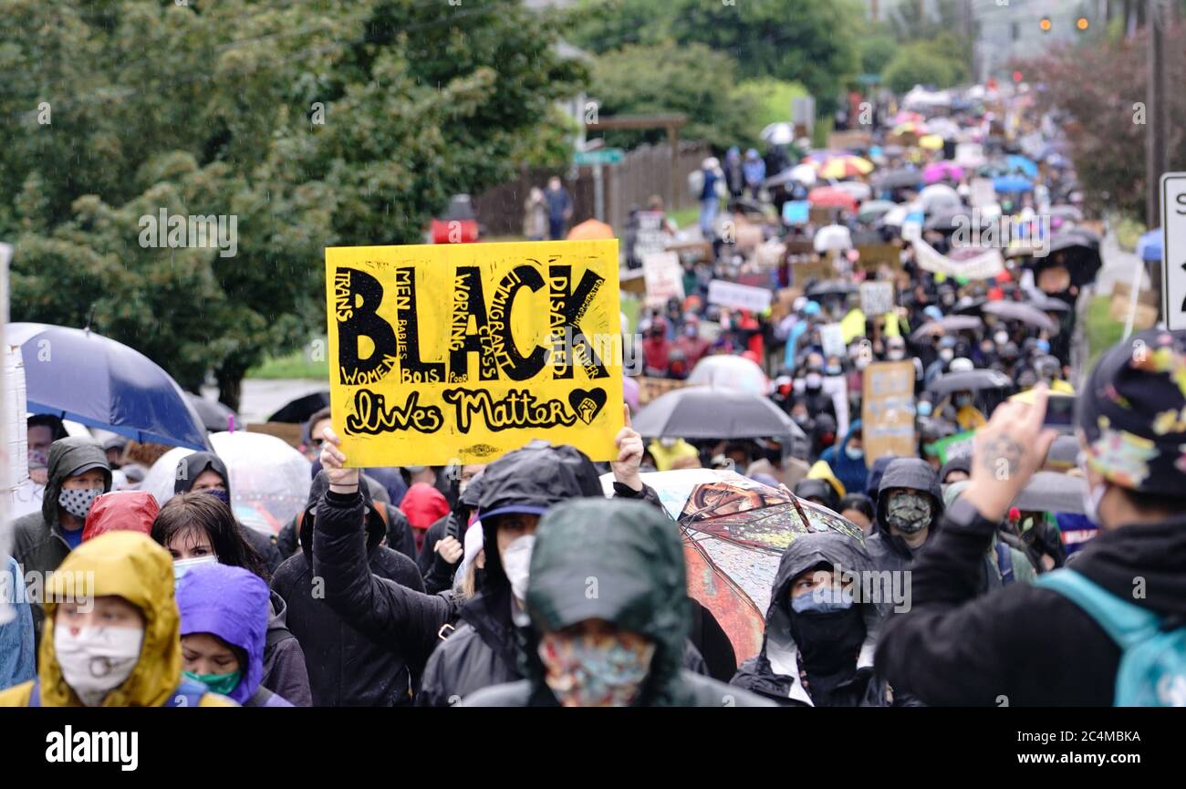 I manifestanti silenziosi marciano sotto la pioggia attraverso i quartieri di Seattle richiamando l'attenzione sul movimento Black Lives Matter e sulla brutalità della polizia Foto Stock