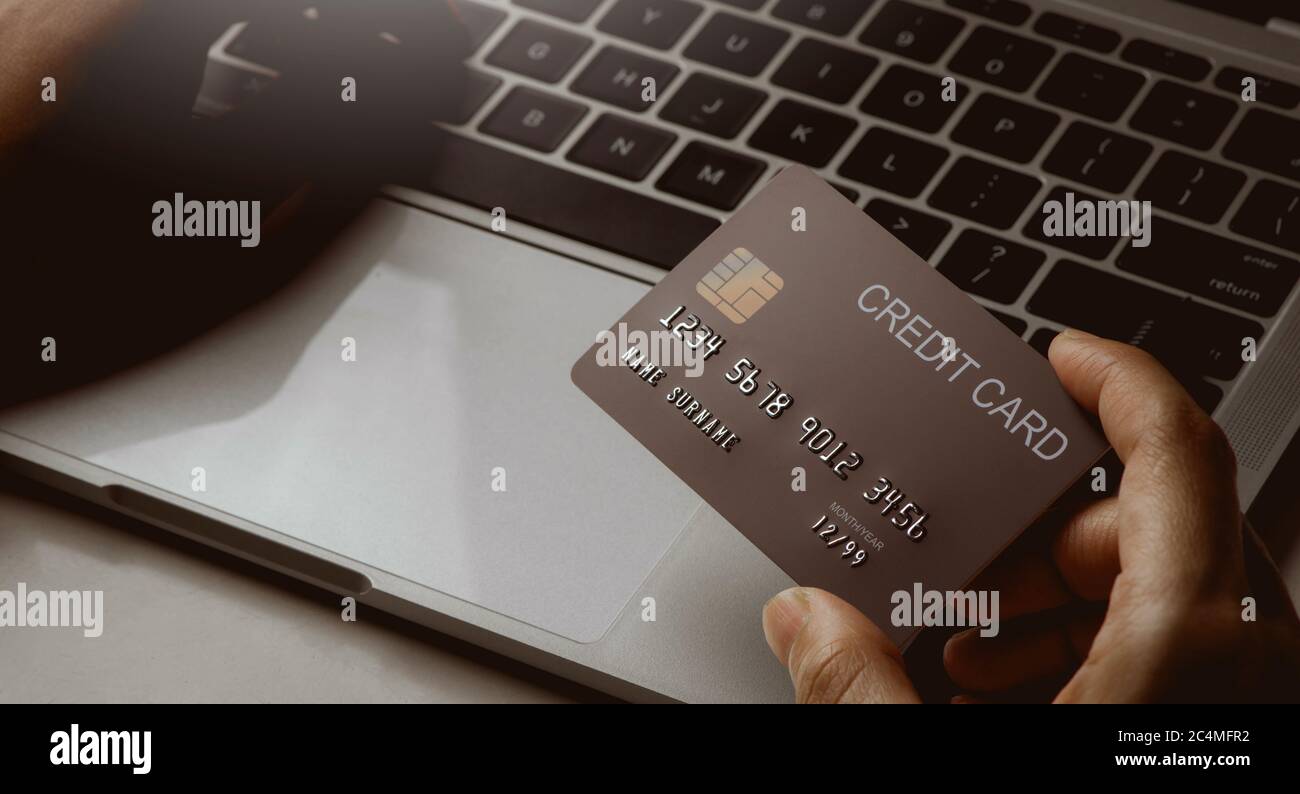 Chiodare le mani tenendo la carta di credito e utilizzando il computer portatile. Acquisto online e concetto di pagamento. Foto Stock