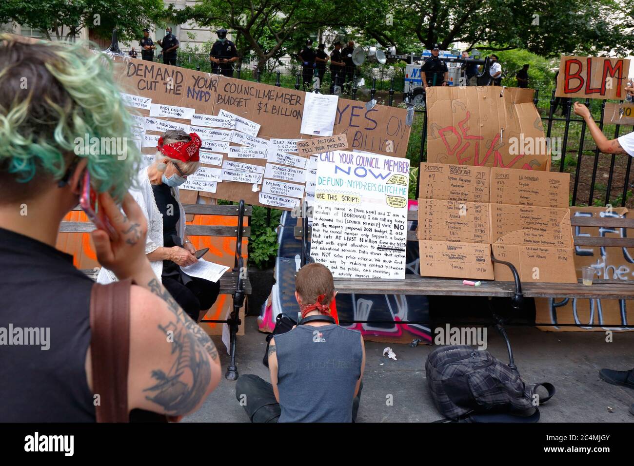 New York, New York. 26 giugno 2020. Le persone in una stazione di azione legislativa presso Occupy City Hall con un cartello su come contattare i membri del New York City Council per chiedere di tagliare il budget di NYPD di 1 miliardo di dollari. Attivisti con voci di attivisti e leader della comunità (VOCAL NY) E gli alleati hanno occupato un parco adiacente al Municipio prima della scadenza del 1° luglio per esercitare pressioni sul sindaco e sul consiglio comunale affinché definanziino il NYPD di almeno 1 miliardo di dollari dal loro budget annuale di 6 miliardi di dollari per reinvestire in alloggi, assistenza sanitaria, istruzione e servizi sociali. Foto Stock