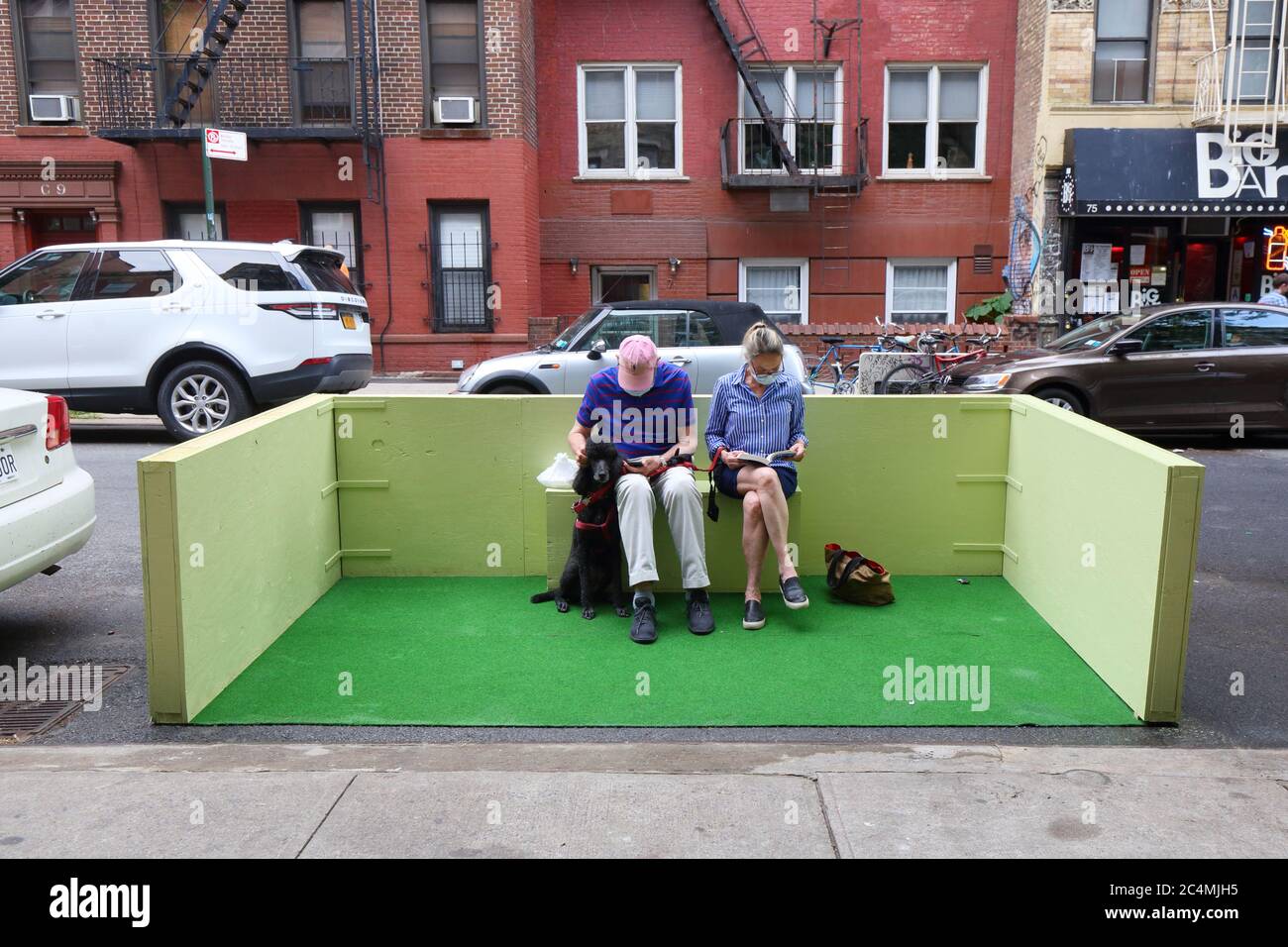 New York, New York. 27 giugno 2020. Due persone e un cane seduti in un parco nel quartiere di East Village di Manhattan. I parcheggi sono estensioni laterali su una corsia di parcheggio di una strada o di una strada per aumentare lo spazio pubblico. Con la riapertura della fase 2 di New York City che consente ai ristoranti di servire i clienti, i parchi vengono utilizzati per cene all'aperto socialmente distanziate. Foto Stock