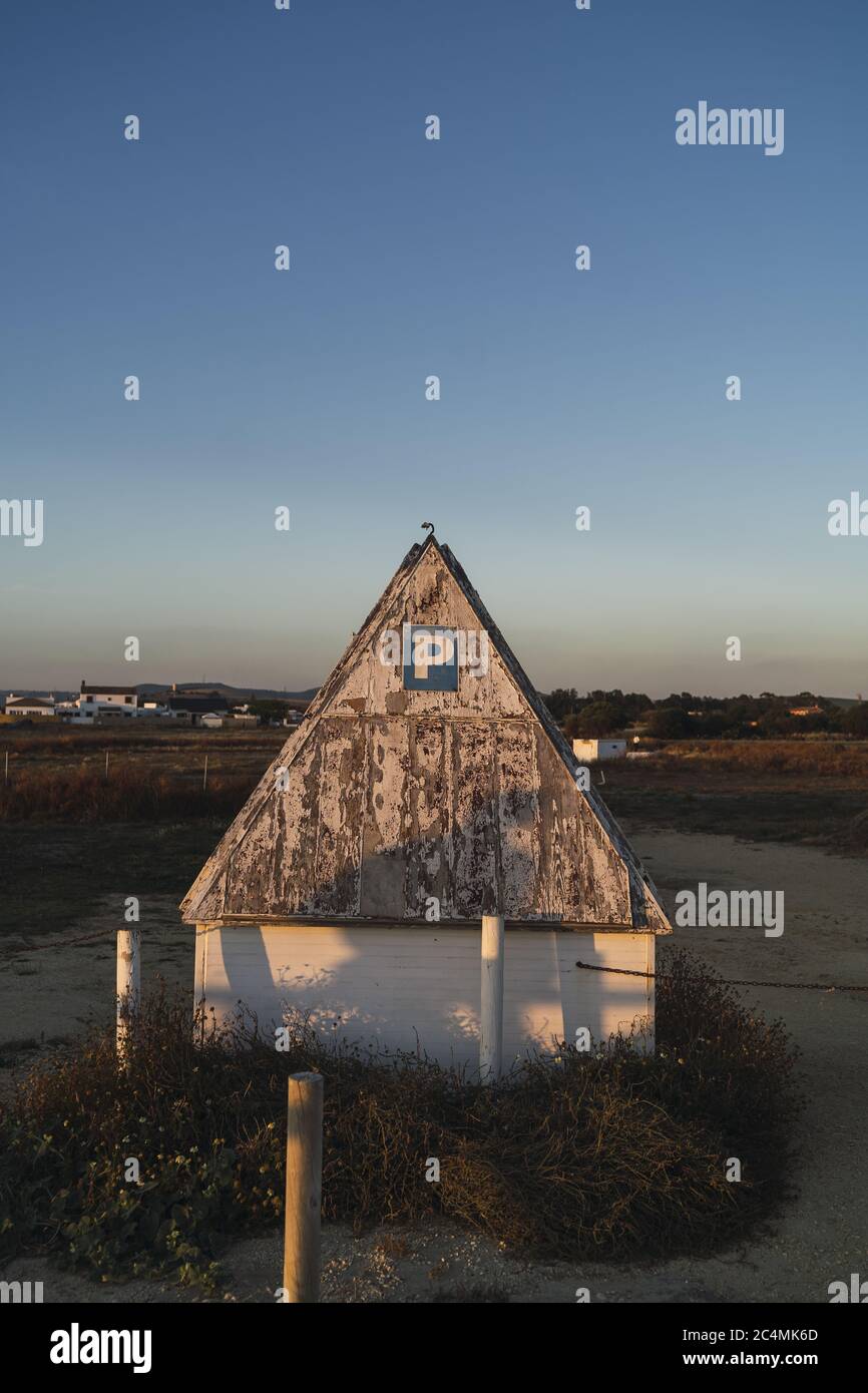 Vecchio piccolo edificio con tetto usurato e un blu cartello parcheggio su di esso Foto Stock