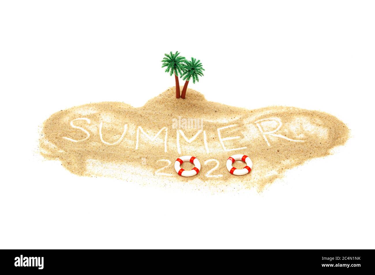 Isola tropicale giocattolo in miniatura con palme isolate su bianco. Il testo SUMMER 2020 è scritto nella sabbia. Concetto di vacanza creativo. Foto Stock