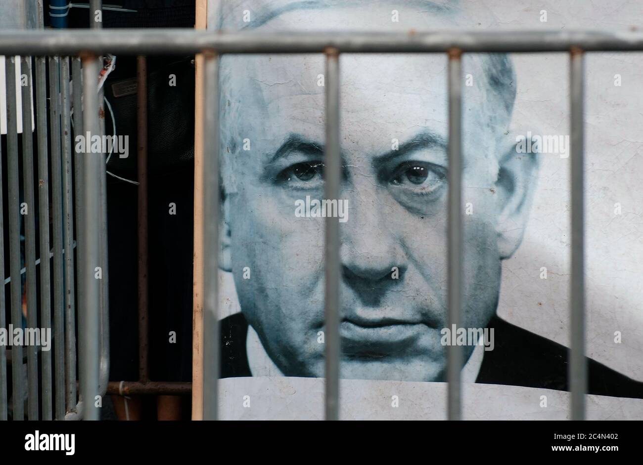 Gerusalemme, ISRAELE 27 giugno 2020: Un poster che mostra il ritratto di Benjamin Netanyahu behinds Bars è visto come centinaia di sostenitori del movimento anti-corruzione bandiera nera che si esibisce fuori dalla casa del primo ministro Benjamin Netanyahu, chiedendo di dimettersi alla luce delle accuse di corruzione contro di lui a Gerusalemme, Israele. Credit: Eddie Gerald/Alamy Live News Foto Stock