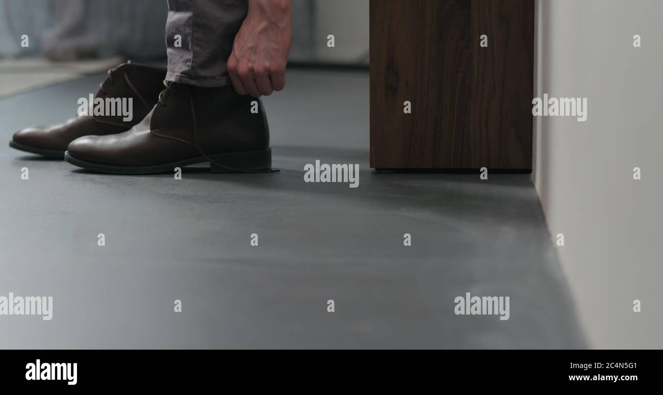 il giovane uomo togli gli stivali chukka in pelle marrone al coperto Foto Stock