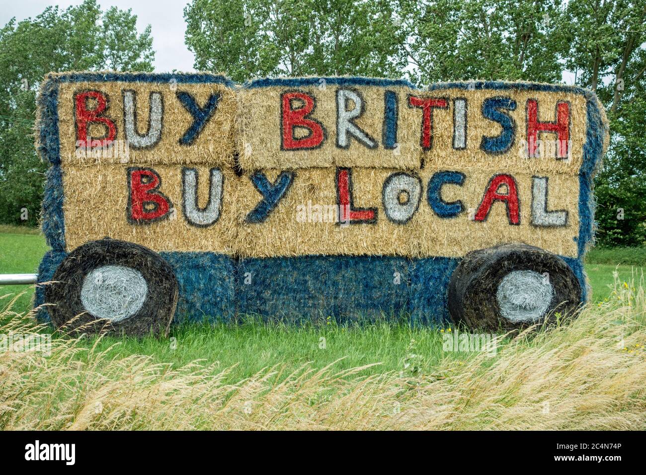 Acquista British acquistare slogan locale dipinto su lato di balle di paglia, Cambridgeshire, Inghilterra Foto Stock