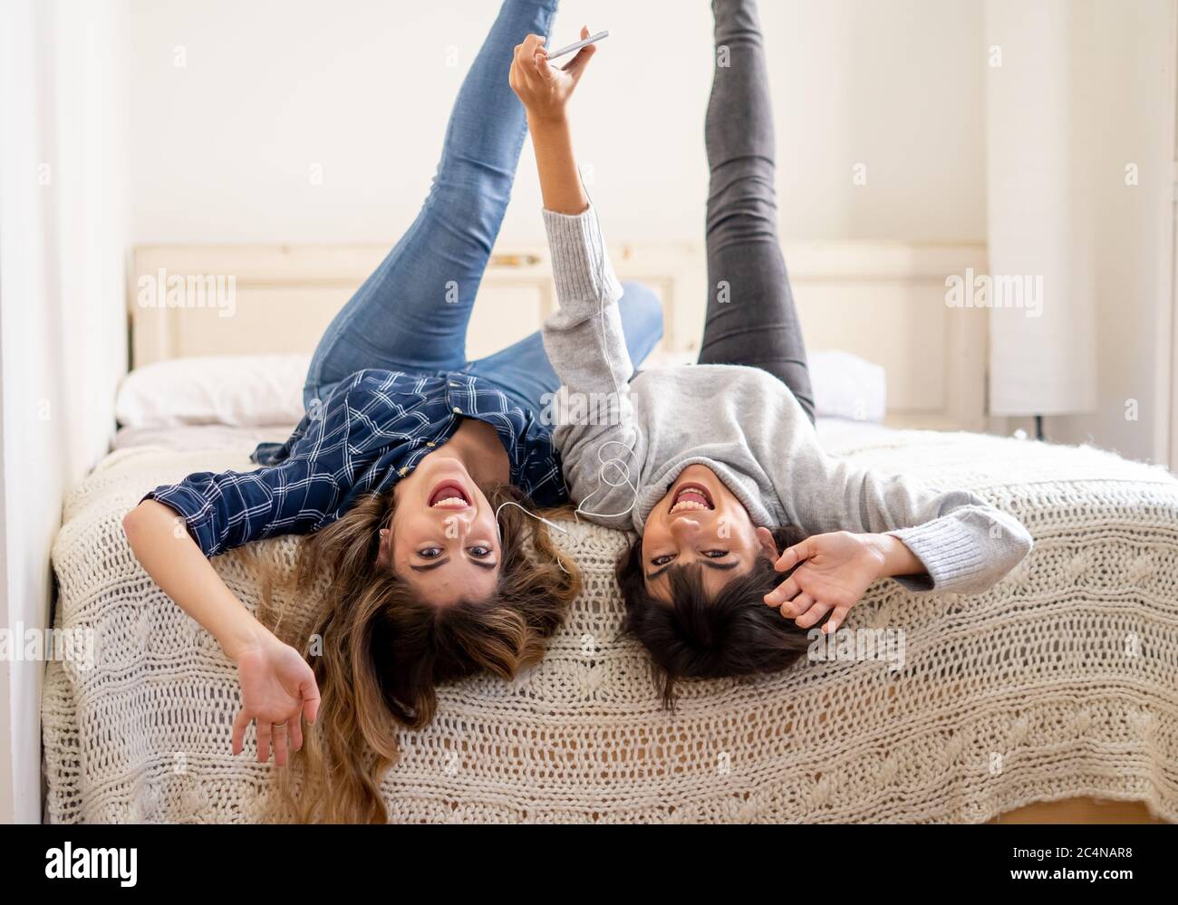 Blocco COVID-19. Ritratto di donne fidate e positive fidanzate ascoltare musica online insieme sul telefono cellulare durante coronavirus sociale dist Foto Stock