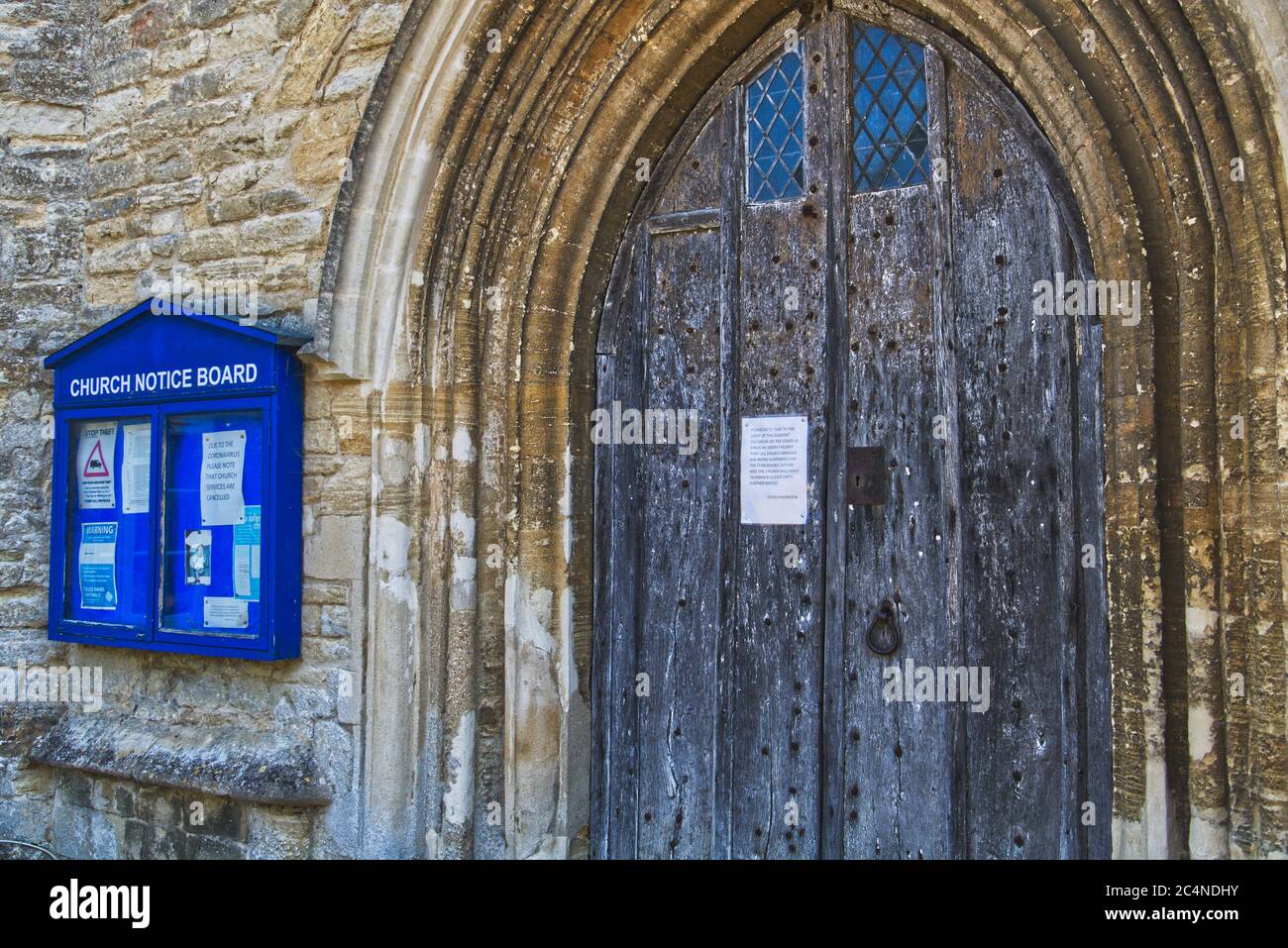 Chiesa porta e bacheca con segni di chiusura a causa del covid-19 al villaggio di Harrold nel Bedfordshire, Regno Unito Foto Stock