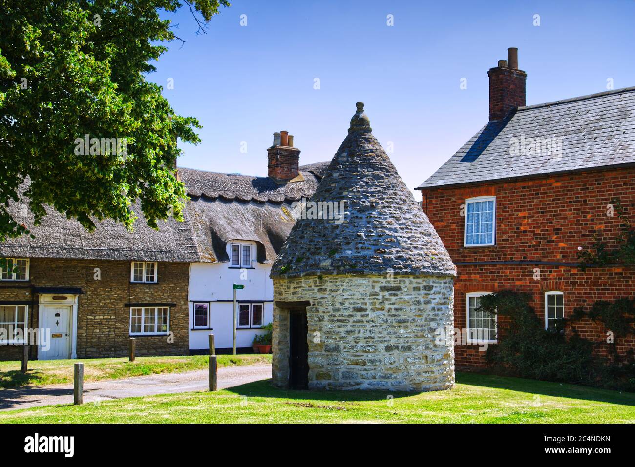 Il vecchio villaggio Lock Up Jail o Blind House circondato da cottage sul verde in Harrold, Bedfordshire, Regno Unito Foto Stock
