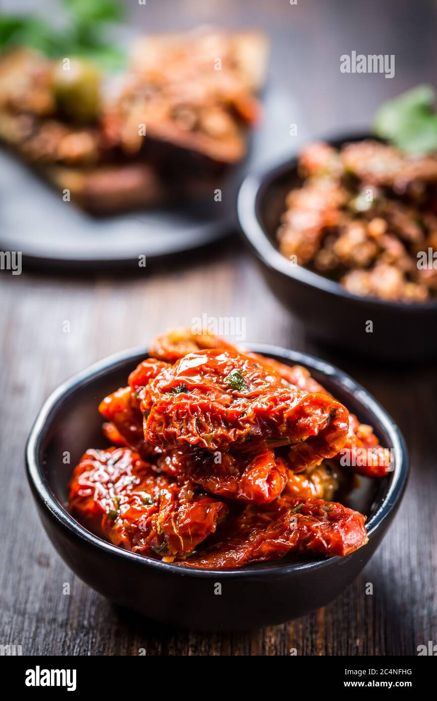 Pomodoro essiccato al sole con olio d'oliva come antipasto con tapenade e bruschetta sullo sfondo Foto Stock