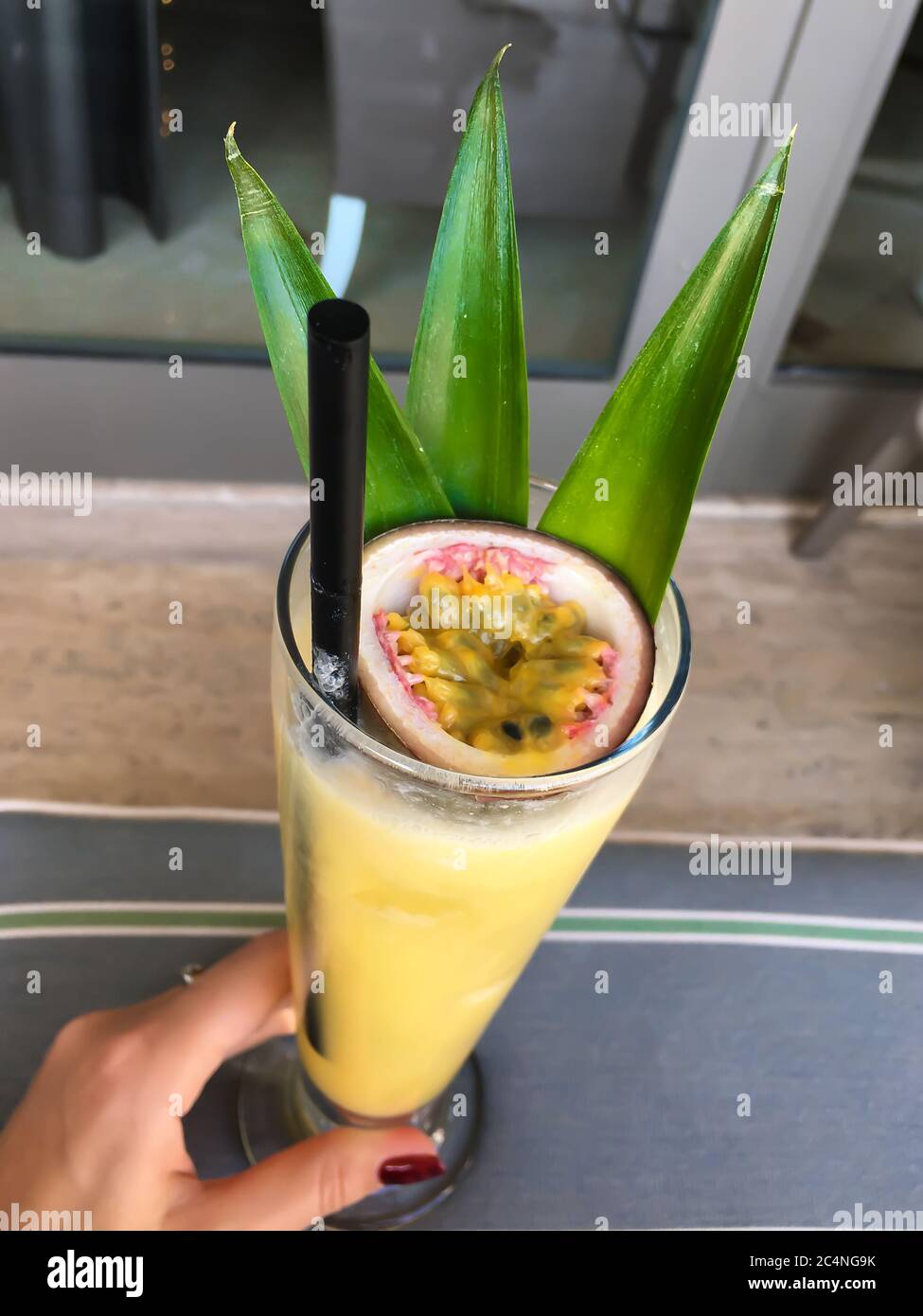 Delizioso cocktail esotico giallo rinfrescante con frutto della passione in  mano alla ragazza Foto stock - Alamy