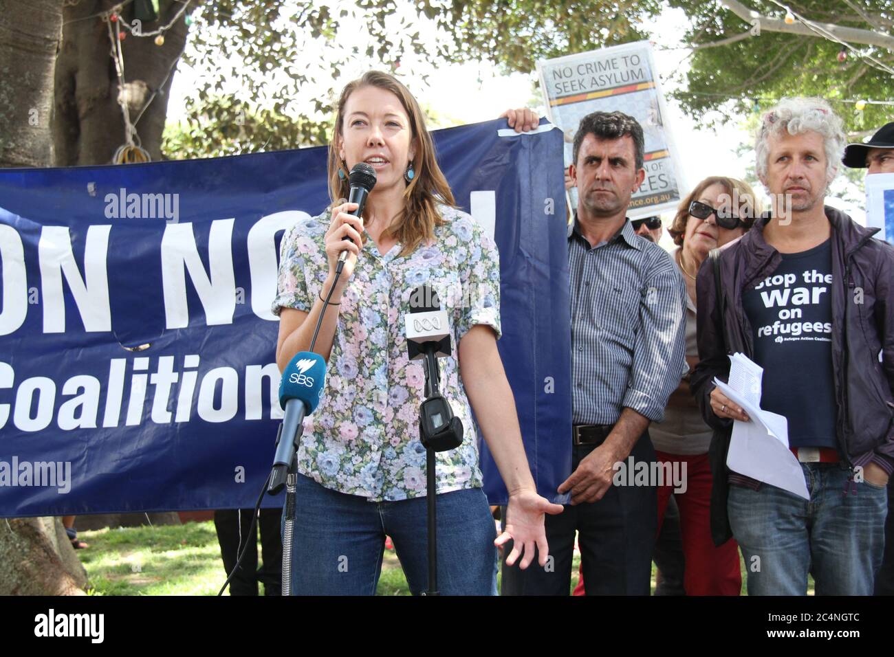 Il MC, un repressivo della Coalizione per l’azione dei rifugiati, parla ai manifestanti riuniti a Manly prima della marcia nell’ufficio di Tony Abbott. Foto Stock