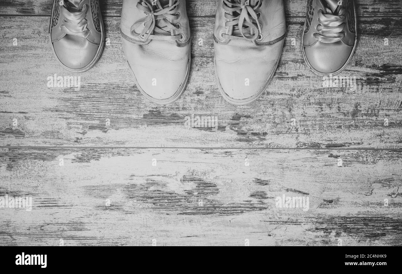 Scarpe bianche padre e figlia su elegante sfondo in legno shabby. Concetto di giorno dei padri. Foto Stock