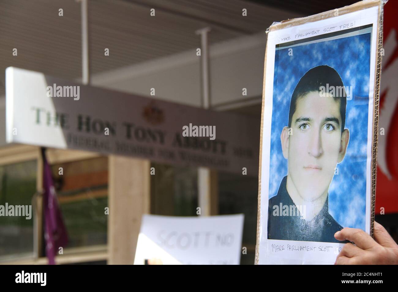 Un protettore ha un cartello fuori dall'ufficio di Warringah di Tony Abbott a Manly con la foto dell'iraniano curdo Reza Berati, ucciso durante una rivolta Foto Stock