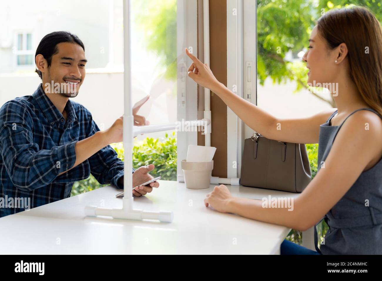 I clienti asiatici si toccano sullo schermo virtuale per selezionare il menu sul tavolo di social distancing per un nuovo stile di vita normale nel ristorante dopo il coronavirus covid-19 pa Foto Stock