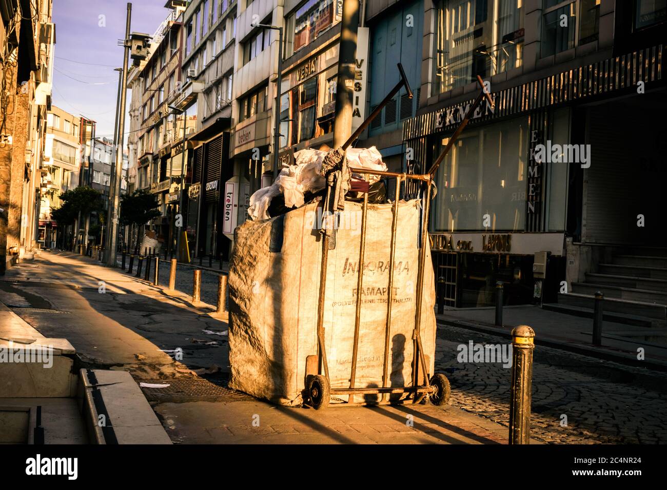Riciclaggio di carta, plastica, ecc. in città, cultura della vita urbana. Riciclare carriola sul marciapiede con il sole dolce l Foto Stock