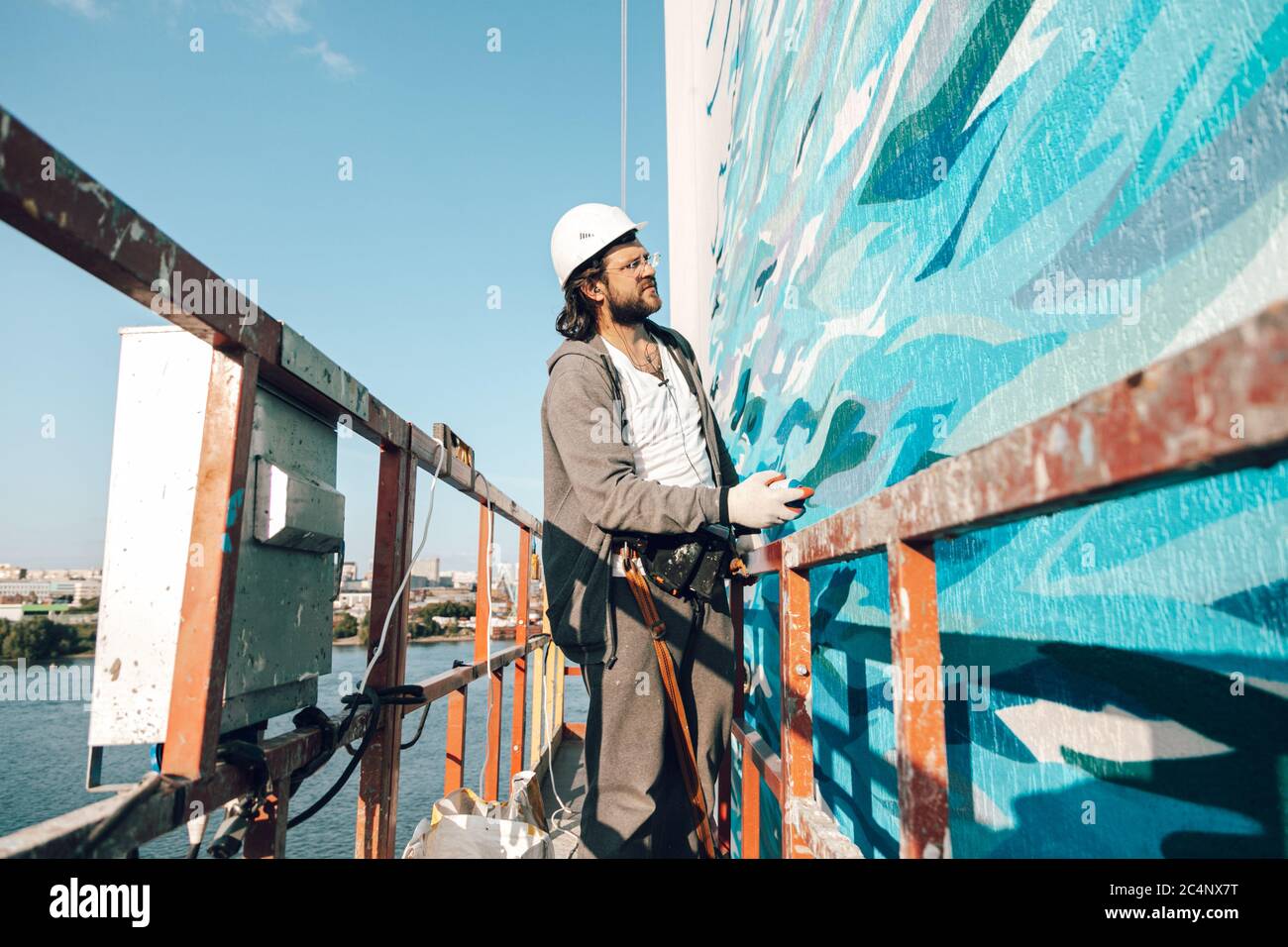 L'artista Graffiti dipinge una parete bianca ad alta quota in onde. Graffiti consentiti da tutte le regole Foto Stock