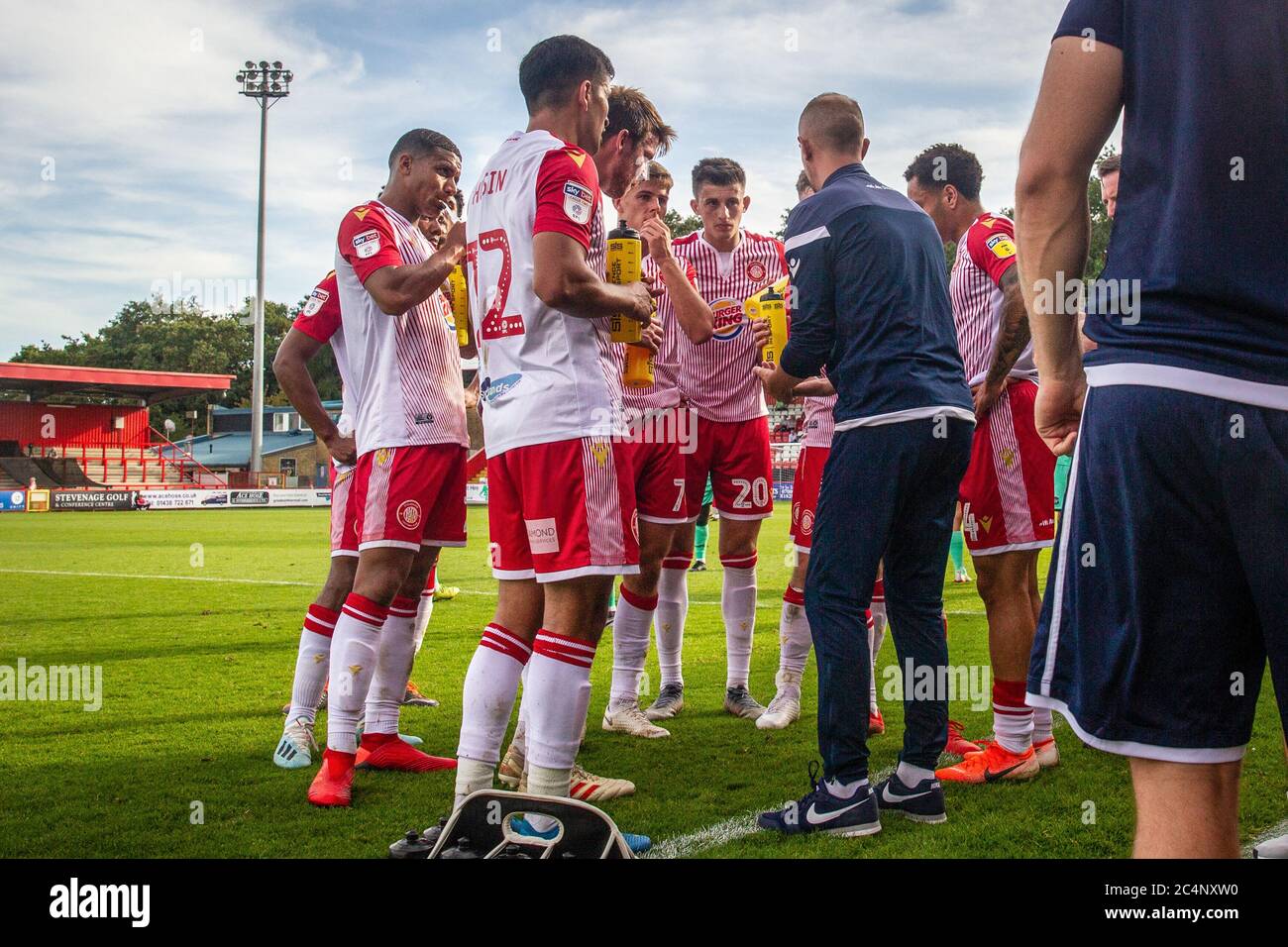 I giocatori di calcio si levano in piedi in semicerchio durante la pausa delle bevande nella partita di campionato professionale ascoltando il capo allenatore Foto Stock I giocatori di calcio si levano in piedi in semicerchio durante la pausa delle bevande nella partita di campionato professionale ascoltando il capo allenatore Foto Stock