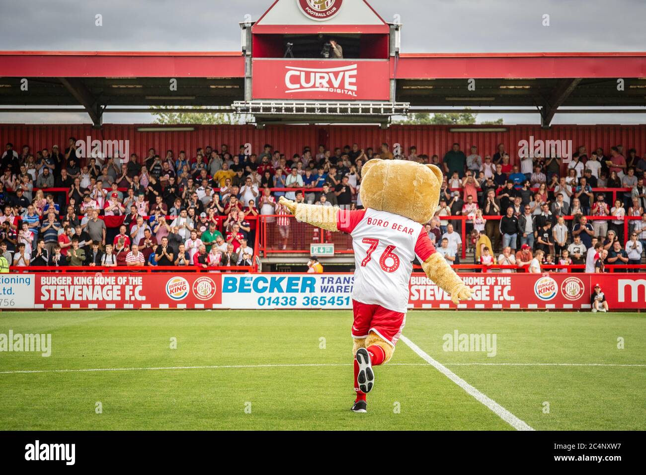 mascotte della squadra di calcio che corre verso i tifosi all'inizio della partita di calcio / calcio in campionato professionale. Foto Stock