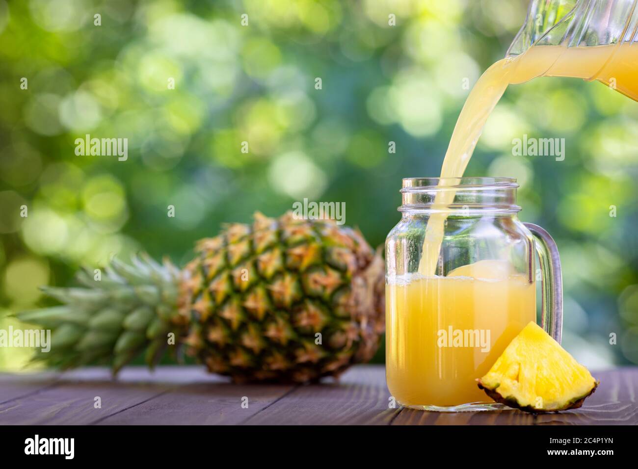 succo di ananas che si versa nel vasetto di muratore Foto Stock