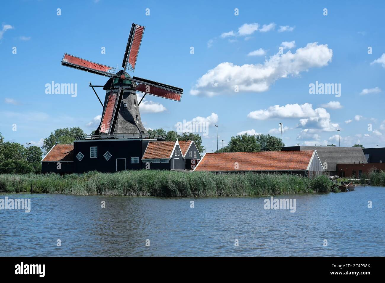 Europa, Paesi Bassi - Tour attraverso i canali di Friesland, un molo con una barca a vela, sullo sfondo un mulino a vento tradizionale Foto Stock