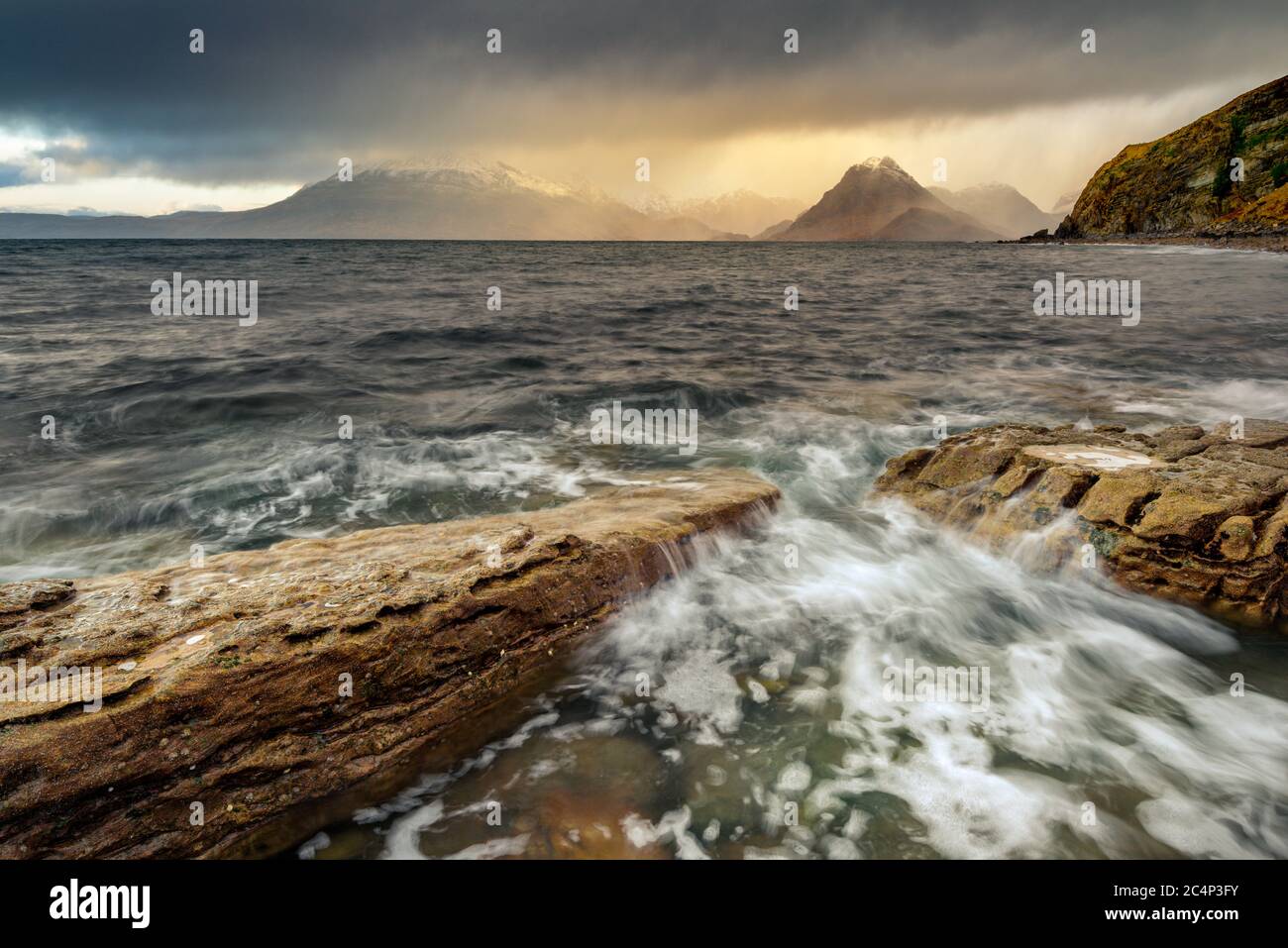 Nuvole scure e Moody con pioggia che passa sulle Montagne Scozzesi delle Highland con onde che si infrangono sulle rocce sulla Shoreline. Elgol, Isola di Skye, Regno Unito. Foto Stock