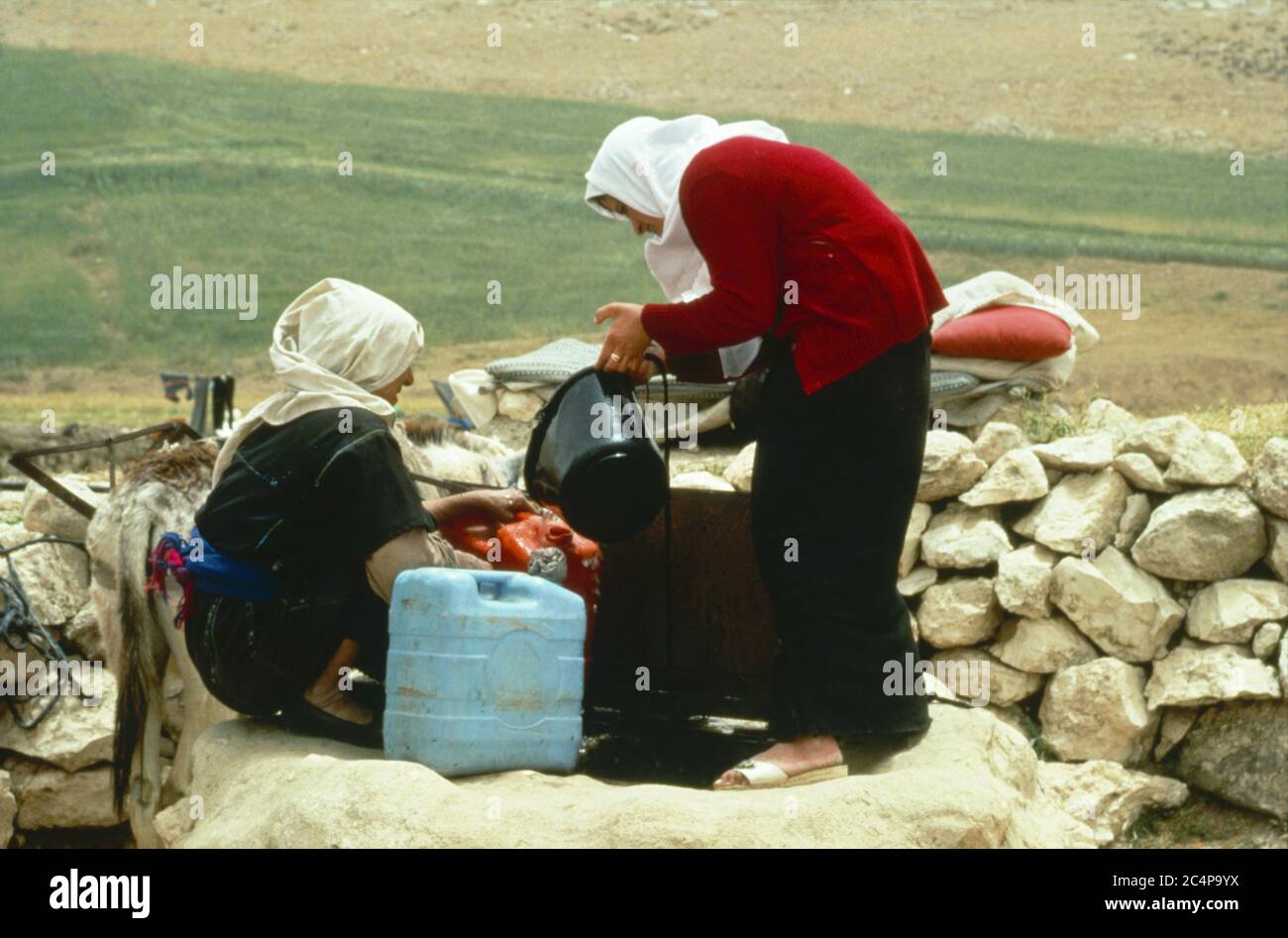 Due donne che raccolgono acqua da un pozzo, Israele Foto Stock